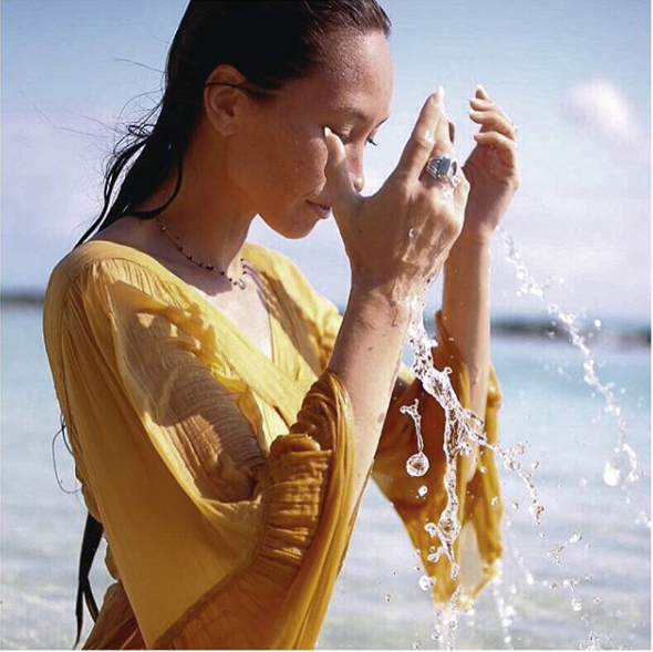 beautiful woman splashing water on her face from the oceans of Hawaii | Honua Hawaiian Skincare
